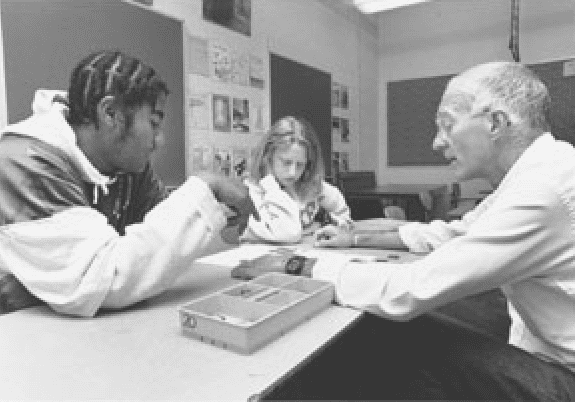 Rudd Crawford sitting at a table with two students, discussing math problems.
